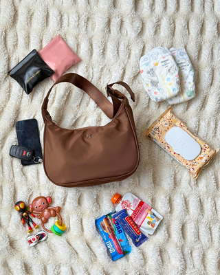 packing image of Emmy bag with 2 diapers, 2 clutches, keys, phone, wipes, snacks, & toys